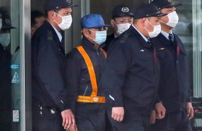 Guardas de un centro de detención escoltan, este miércoles, a un hombre (2i) que se cree podría ser el expresidente de Nissan Motor, Carlos Ghosn, al quedar en libertad bajo fianza en Tokio (Japón).